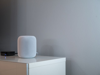 Smart wireless speaker at home to play music. Grey an white background.