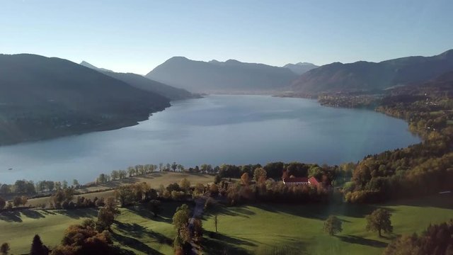 4k Panoramic drone flight from North Part of the Lake Tegernsee at sunset with fog in autumn. The lake is one of the cleanest lakes in Bavaria and is a popular tourist destination.