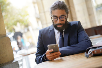 Businessman sitting at restaurant table using smartphone