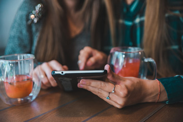 two women talking in cafe drinking tea looking tablet