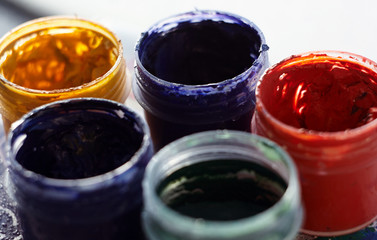 five jars of gouache in different colors on a light background