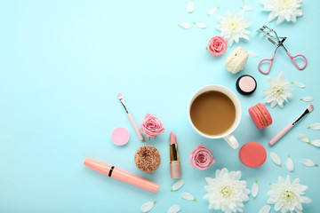 Fototapeta na wymiar Flowers with cup of coffee and makeup cosmetics on blue background