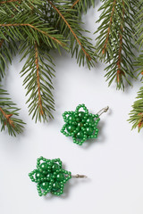 Women's earrings made of beads among the branches of spruce. On a white background.