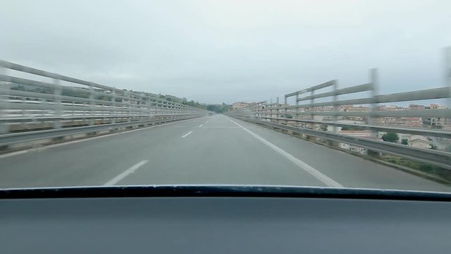 Approaching and driving into tunnel on the E90 with town of Campofelice di Roccella visible below in Sicily, Italy.