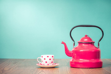 Retro classic red kettle and cup of tea with polka dots on oak wooden table in front aquamarine...
