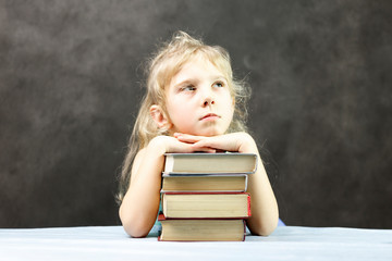 little girl blonde lies on the book. and dreams. in the background is a formula board. shallow depth of cut. have toning.