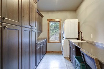 Laundry room with lots of space and floor to ceiling dark cabinets.