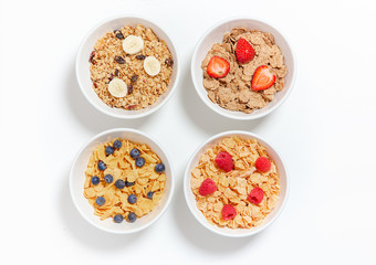 bowls of different breakfast cereals with berries and fruits. cornflakes, granola and cereal on a white background. flat lay, top view 