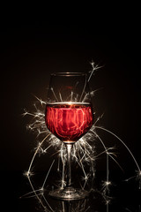 Rotweinglas mit feierlicher Wunderkerze