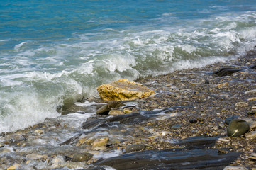 pebble stones on the sea beach, the rolling waves of the sea with foam