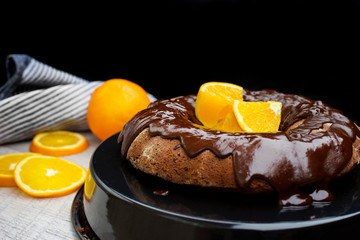 Dark chocolate  cake with  Oranges on wooden background.