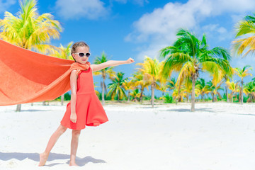 Little cutie girl playing superhero at a tropical beach