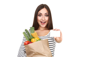 Beautiful woman holding blank card and grocery shopping bag on white background