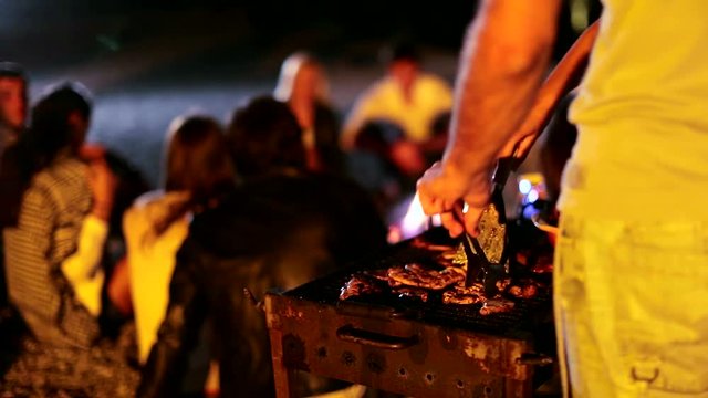 Young people make a barbecue on the beach at night