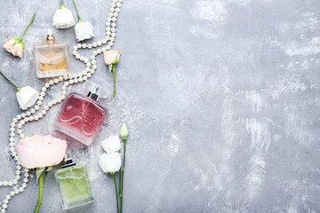 Perfume bottles with flowers on grey wooden table