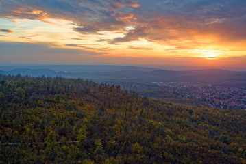 Sunset over wooded hills and city suburbs in autumn. 