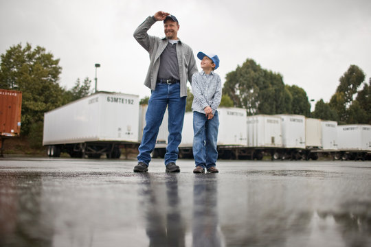 Young boy walking with his father standing in an outdoor freight yard.