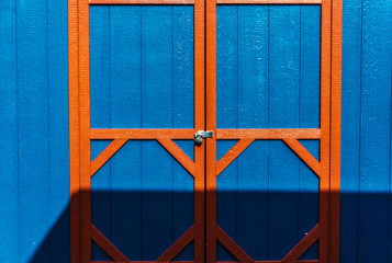 Red framed doors of blue wooden shed