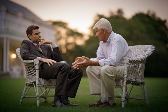 View of two gentlemen in formal attire having a conversation. - Powered by Adobe
