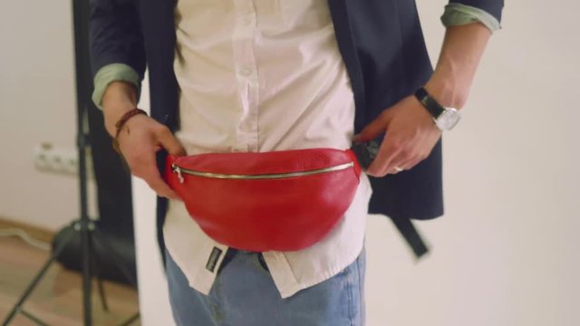 Guy in jeans, black jacket and white shirt tries on fanny pack