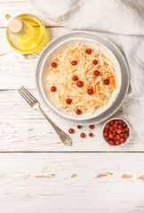 Cabbage salad. Traditional russian appetizer sauerkraut with cranberry and carrot in a plate on a white wooden table.  Rustic style
