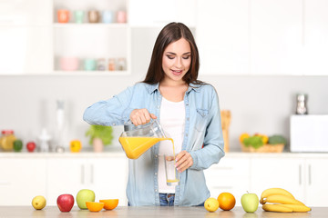 Beautiful woman pouring orange juice in the glass