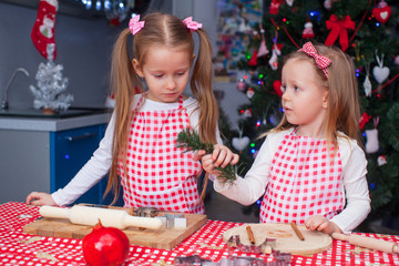 Two little girls make gingerbread cookies for Christmas