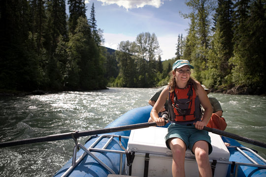 Young adult woman rowing along a river.