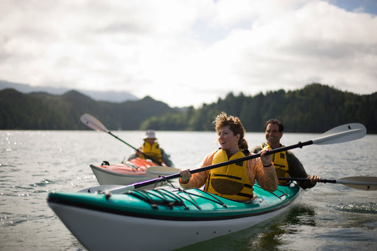 Happy mid-adult couple kayaking on a lake with their teenage son.