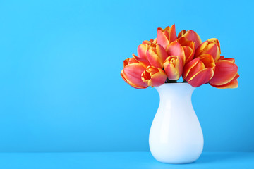Bouquet of tulips in vase on blue background