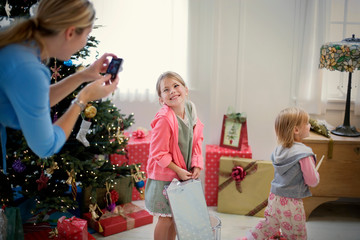 Happy young girl posing for a photograph while unwrapping presents on Christmas Day.