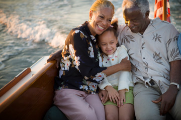 Mature adult couple sitting with their young granddaughter while on a boat.