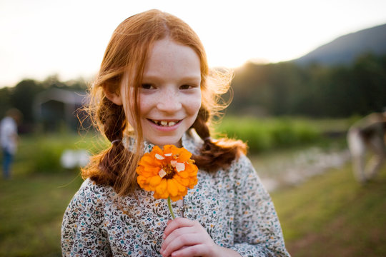 Portrait of a smiling young girl holding a flower.