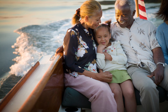 Mature adult couple sitting with their young granddaughter while on a boat.