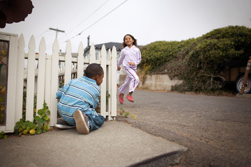Young boy and his young sister playing on a suburban street.