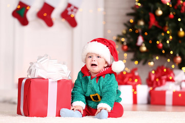 Fototapeta na wymiar Little boy in christmas costume sitting on floor with gift box