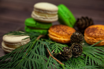 Colorful almond cookies and a Christmas tree with cones on a wooden table