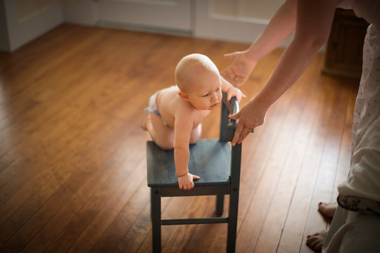 Toddler playing with a small wooden chair in a house.