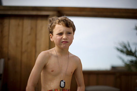 Shirtless young boy wearing identity tags around his neck.