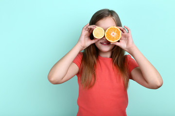 Young girl with orange and lemon fruit on mint background