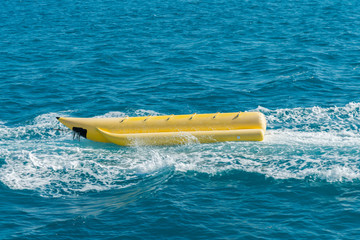 empty inflatable yellow banana boat in the sea. Banana Boat for fun on water surface in summer day - banana boat at the sea