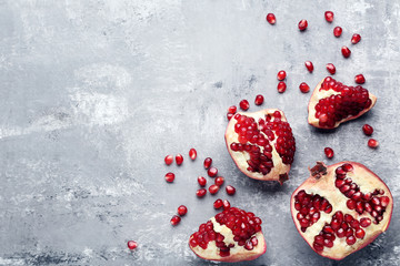 Ripe and juicy pomegranate on grey wooden table