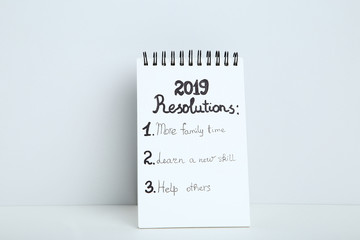 Inscription 2019 resolutions in notepad on grey background