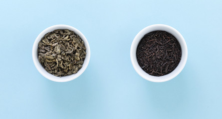 Two white bowls with Black and Green tea, on blue background.