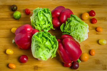 Red bell peppers, romaine lettuce and cherry tomatoes on wooden background