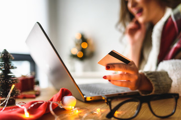 Young woman buying online at home  for winter holidays using laptop computer. Christmas holiday shopping