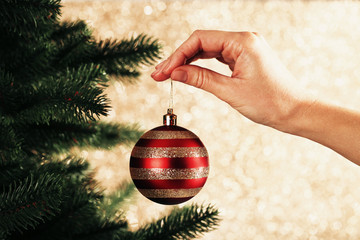 Female hand hanging bauble toy on christmas tree - Powered by Adobe