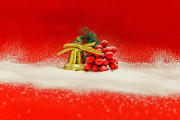 Golden bell and red mistletoe covered with snow on a red background