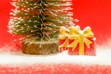 Two gift boxes and Christmas tree covered with snow on a red background