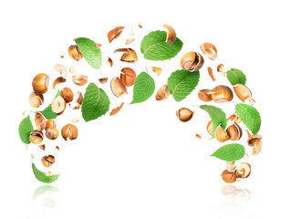 Cracked hazelnuts with leaves in the air isolated a on white background
